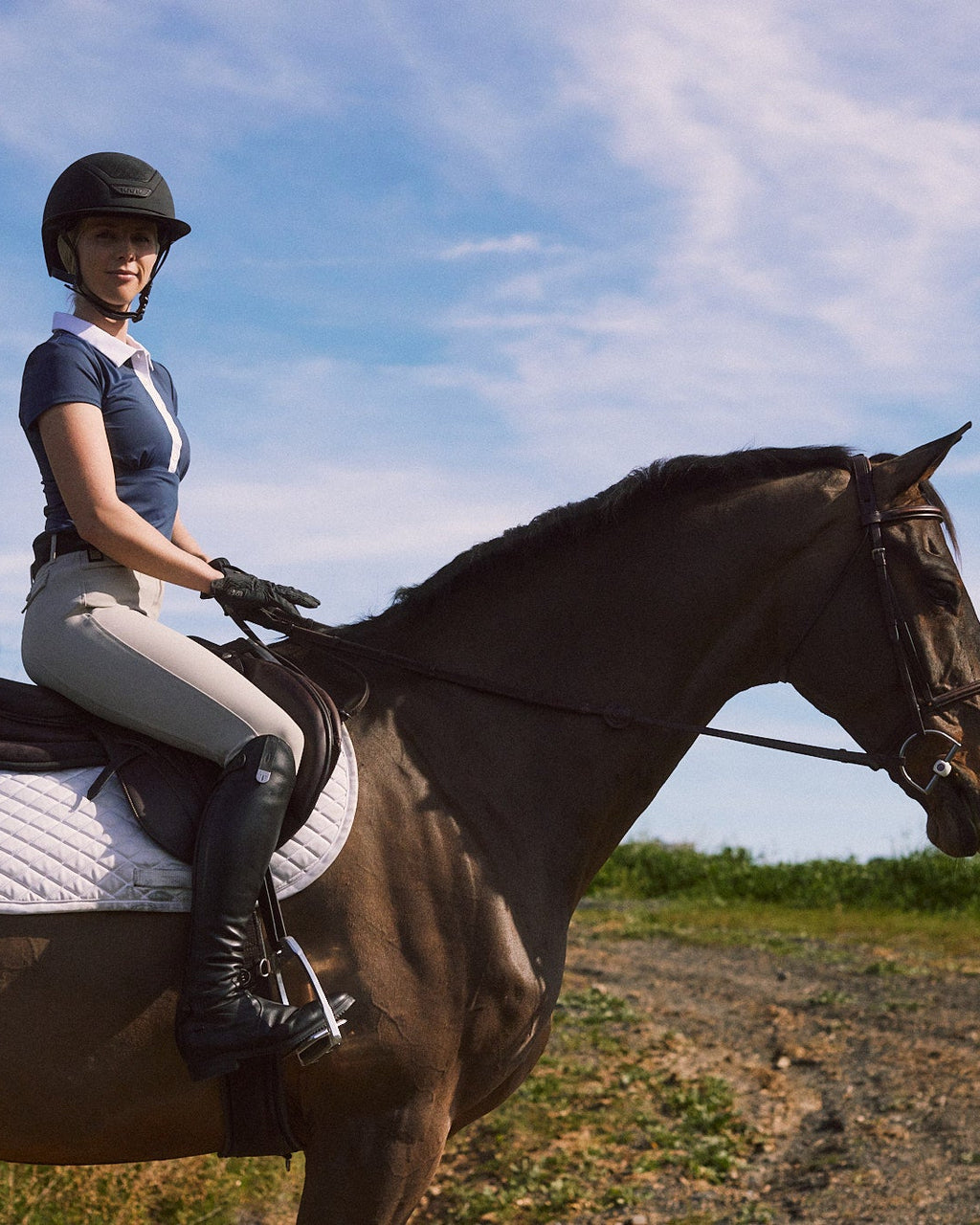 Person riding a horse in an open field with a blue sky.