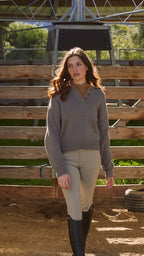 Woman standing in a stable with wooden stalls and a tire in the background