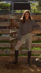 Woman standing in a barn-like setting with wooden walls and a tire on the ground.