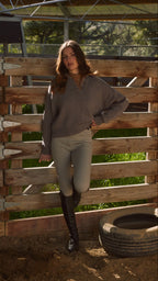 Woman standing in front of a wooden fence with greenery in the background