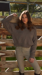 Woman standing behind a wooden fence with greenery in the background