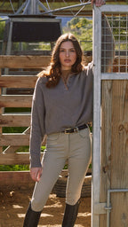 Woman standing in a barn or stable area with wooden stalls and a metal gate.